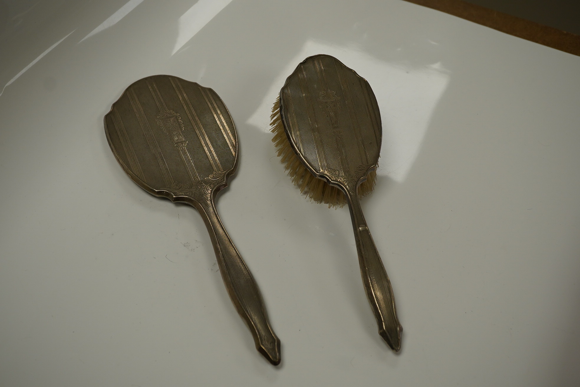 Sundry silver including a silver salver by Garrard & Co, London, 1964, two small dishes, napkin ring, pepperette, a mounted glass butter dish, spoon and a mounted hand mirror and brush, 23.3oz. Condition - poor to fair